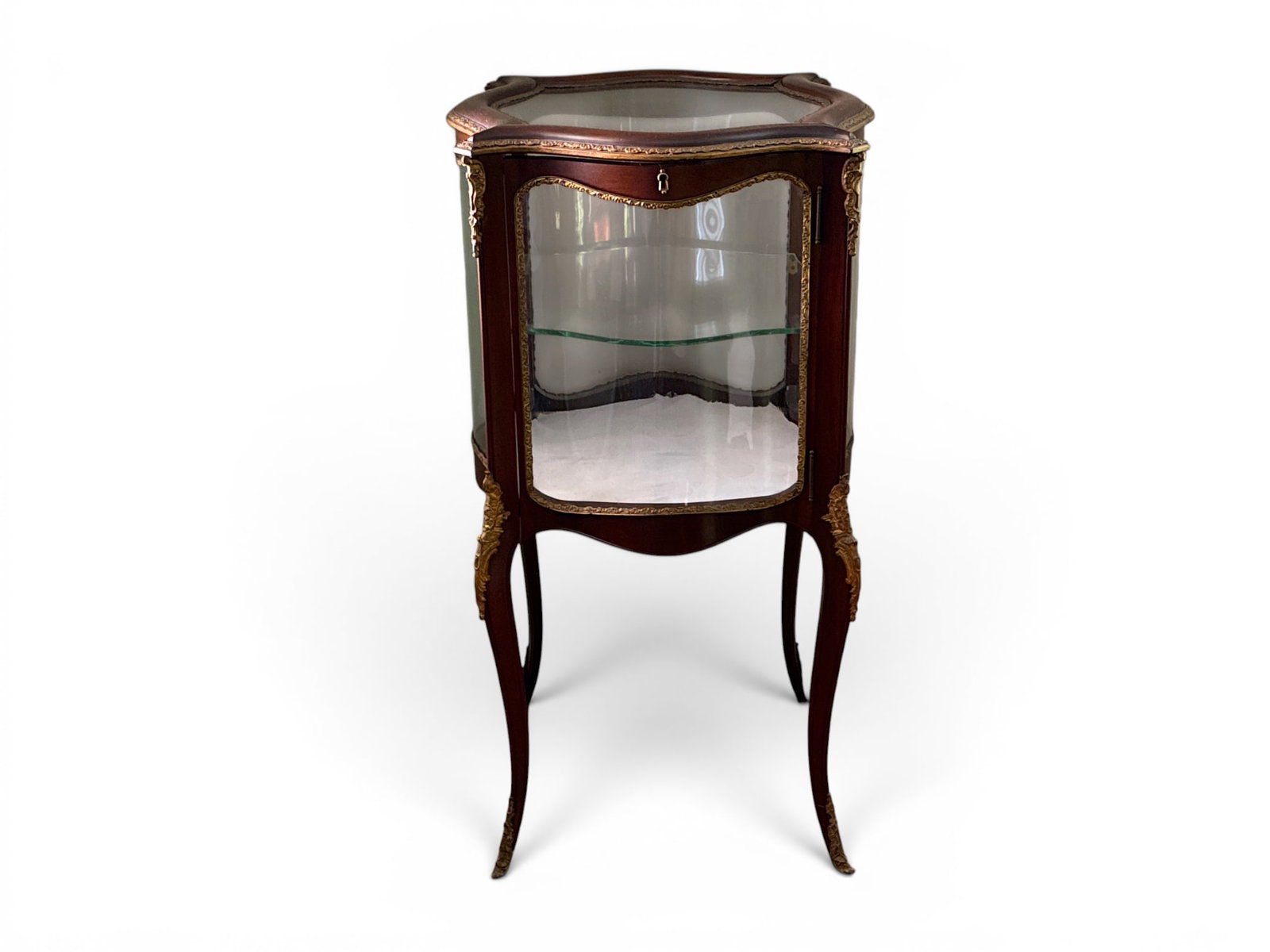 French Louis XV Style Ormolu Vitrine: A French Louis XV-style mahogany vitrine curio having a shaped case with ormolu mounts and serpentine glass, raised on cabriole legs. 38-1/2in tall x 18-1/2in wide. | You have additional shipping