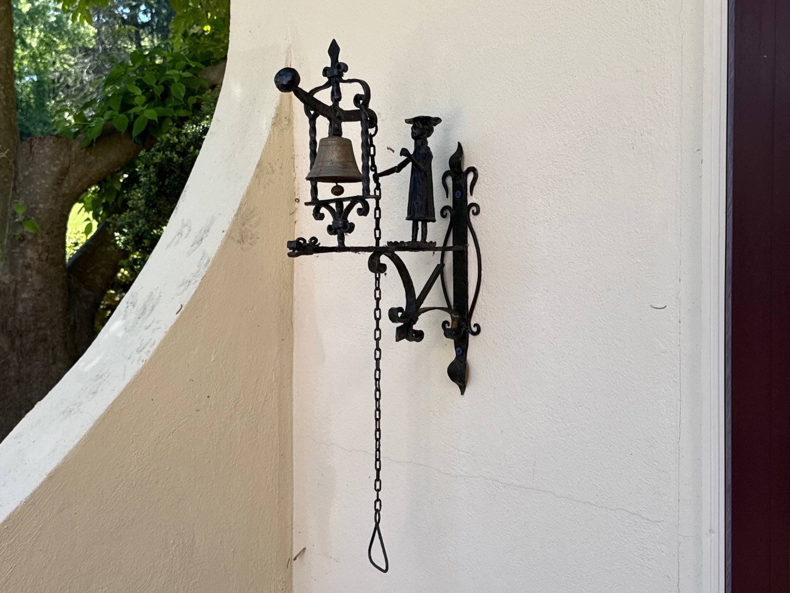 Folk Art Wrought Iron Figural Doorbell: A wrought iron doorbell featuring a standing figure ringing a bell and standing on a stylized dragon plinth. Excluding chain: 21in tall x 7in wide x 13-3/4 in deep. | You have additional shipping opti