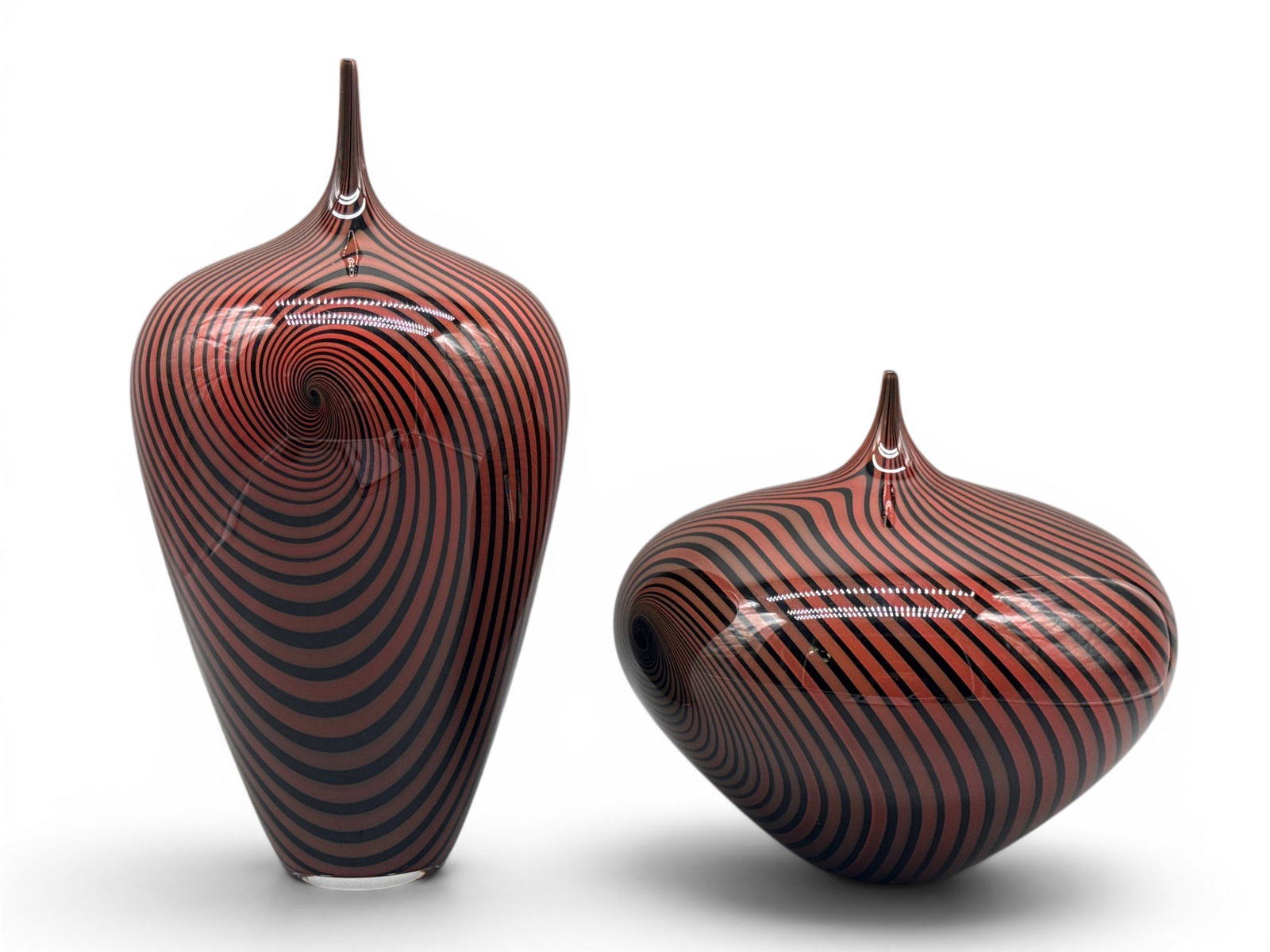Jeff Holmwood. 2 Art Glass Vases.: Jeff Holmwood (Canadian, 20th C) Two art glass vessel having swirling vortex design to include a taller urn form vase and a smaller melon form vase, each with tapering neck. Signed. Larger: 13in tall 