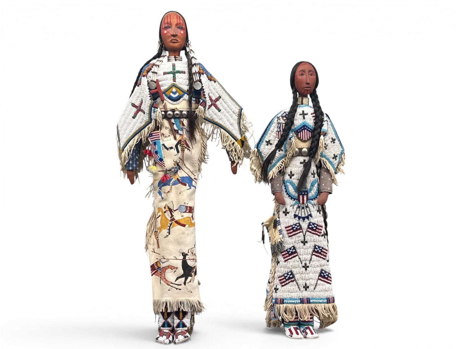 Rhonda Holy Bear Lakota Dolls: Rhonda Holy Bear (Lakota, 20th C.) A pair of Lakota form dolls having hand-beaded buckskin clothing, wood carved bodies, and seed bead ceremonial apparel. 21in tall x 7in wide. | You have additional s