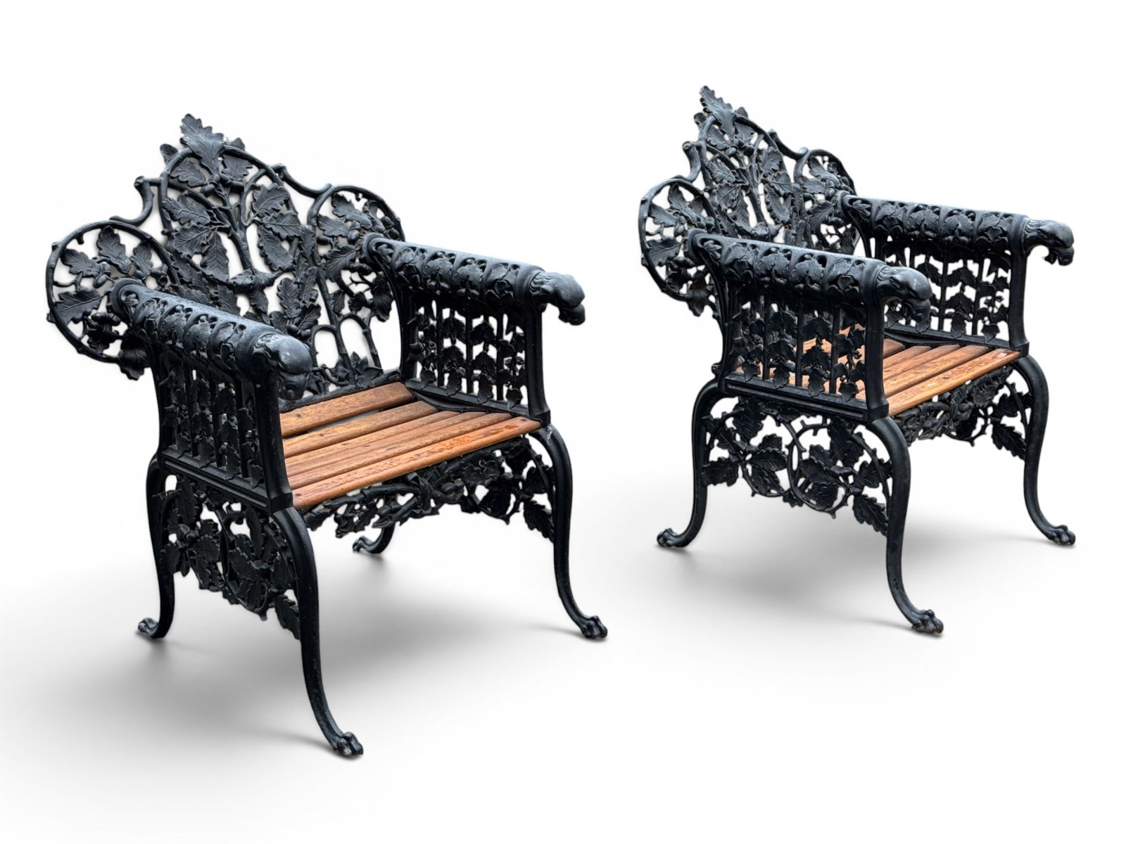 Pair of Cast Iron Oak and Ivy Garden Chairs: A substantial pair of cast iron garden chairs having oak and ivy pierced backs with lion mask handles and wood slatted seats. Chairs: 38in tall x 33in wide x 28 in deep. | You have additional shipping