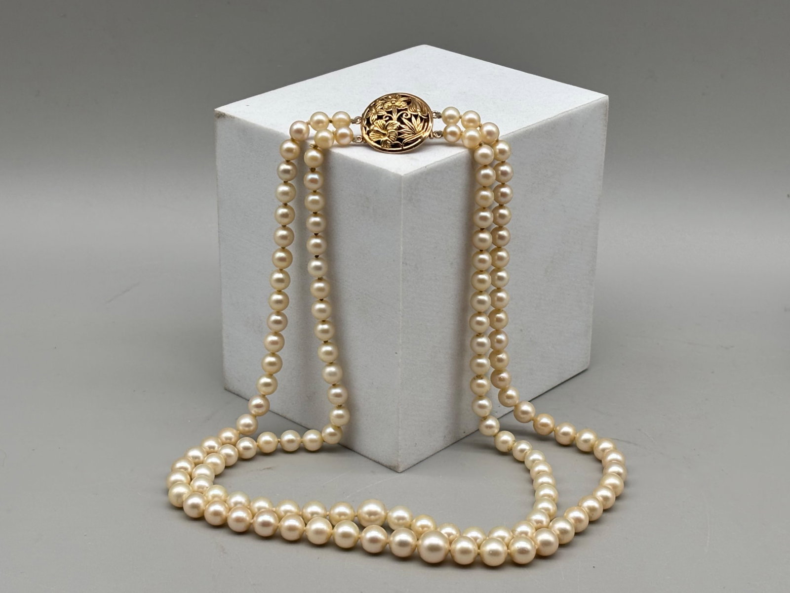 Ming 14K Double-Strand Pearl Necklace: A Ming double-strand graduated pearl necklace having a 14K yellow gold clasp with floral decoration. Stamped Ming / 14K. Largest pearl is 8.5 mm. 18in long. 42.56 dwt. | You have additional shipping o