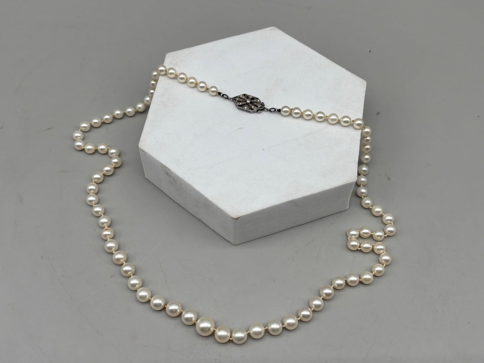 Graduated Pearl Necklace with Platinum and Diamond Clasp: A graduated pearl necklace of 4.7 mm to 8.5 mm pearls with an Art Deco platinum and diamond filigree clasp. 21-1/2in long. 18.84 dwt. | You have additional shipping options, and are not required to us