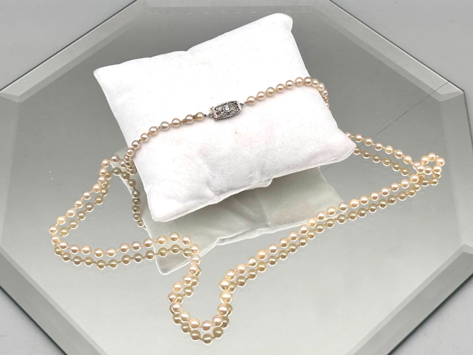 Graduated Pearl Necklace with Platinum and Diamond Clasp: A hand-knotted necklace of 3.9 mm-4.5mm graduated pearls with a platinum Art Deco filigree clasp and brilliant cut central round diamond flanked by four smaller diamonds. 21in long. 7.71 dwt. | You ha