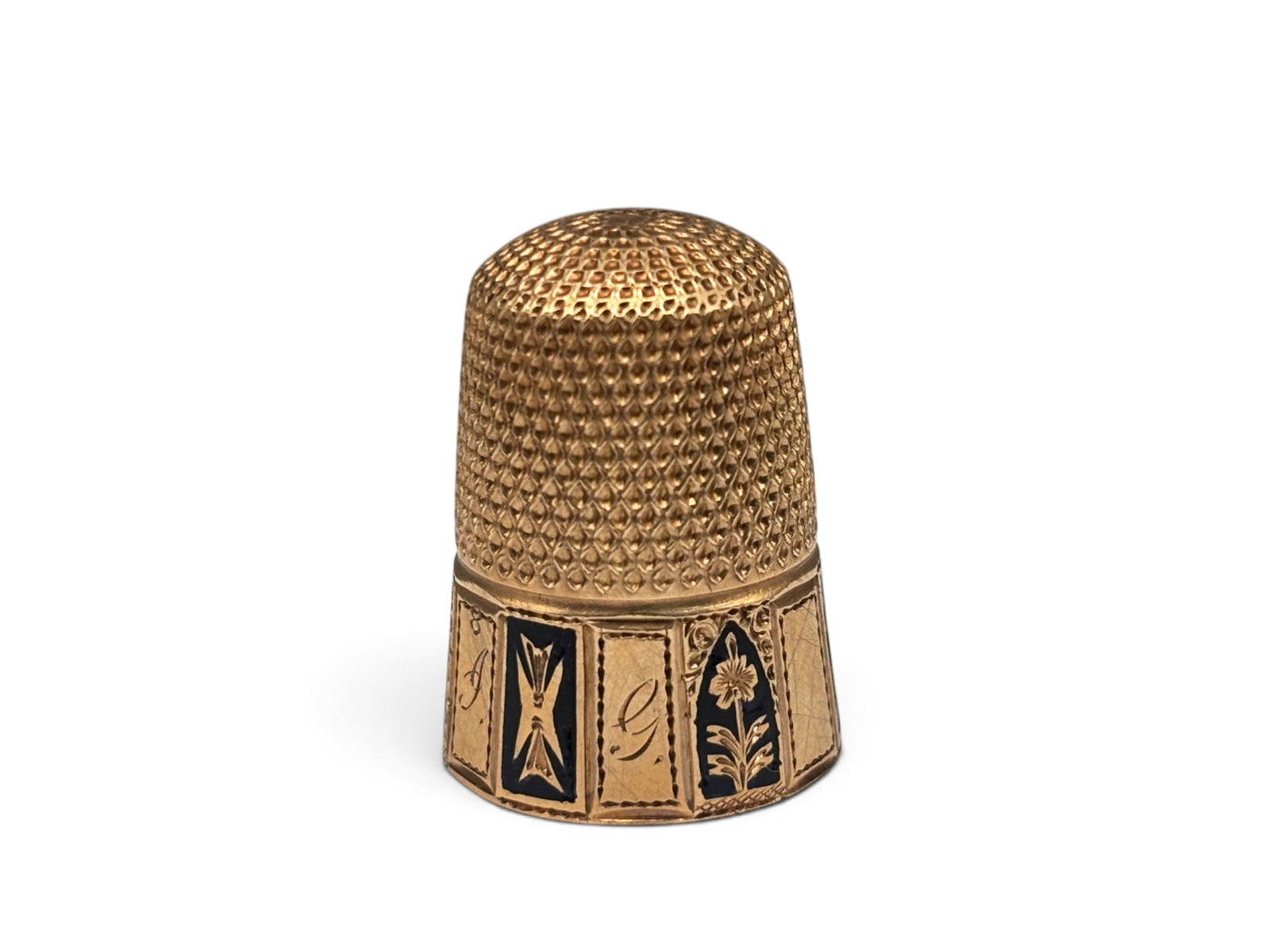 14K Victorian Gold and Enameled Thimble: A 14K Victorian gold thimble with six black enameled panels of botanical and shield designs. Engraved "H", "I", and "G" on separate panels. 3/4in tall x 5/8in wide. 4.24 dwt. | You have additional shi