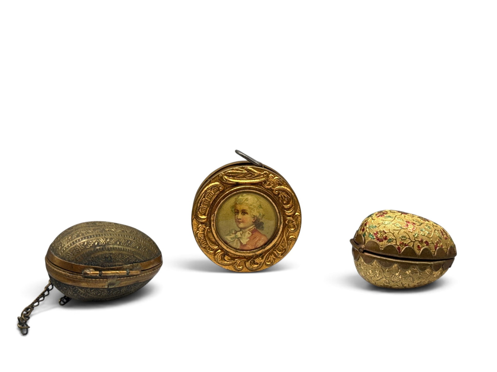 French Victorian Tape Measure and Egg Thimble Cases: Grouping to include a French Victorian gilt brass tape measure with lithograph portrait of noble children, and two gilt brass egg-form thimble cases. Tape measure: 1-1/2in tall x 1-1/2in wide. | You
