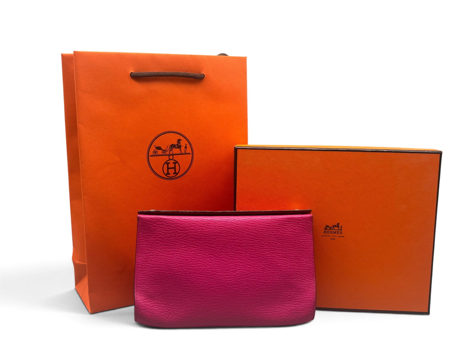 Hermes Karo Leather Pouch: An Hermes Karo leather pouch in framboise with silver tone snap closure and hot pink interior. Marked Hermes on hardware and on interior. Includes original box and bag. 5-1/2in tall x 7-1/2in wide. | 