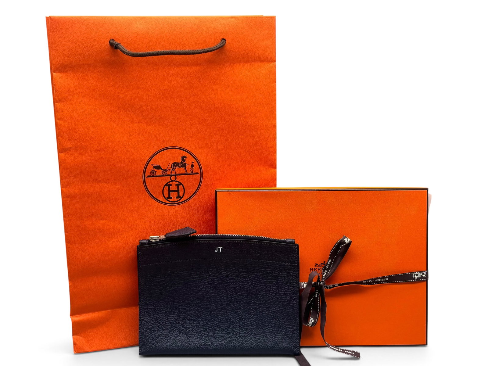 Hermes Pochette Bazar Veau Clutch: An Hermes Pochette Bazar MM Veau Clutch in bleu nuit Togo leather with suede-lined interior and top zip closure. Marked Hermes. Includes original box, bag and ribbon. Monogrammed JT. 6in tall x 8in wi