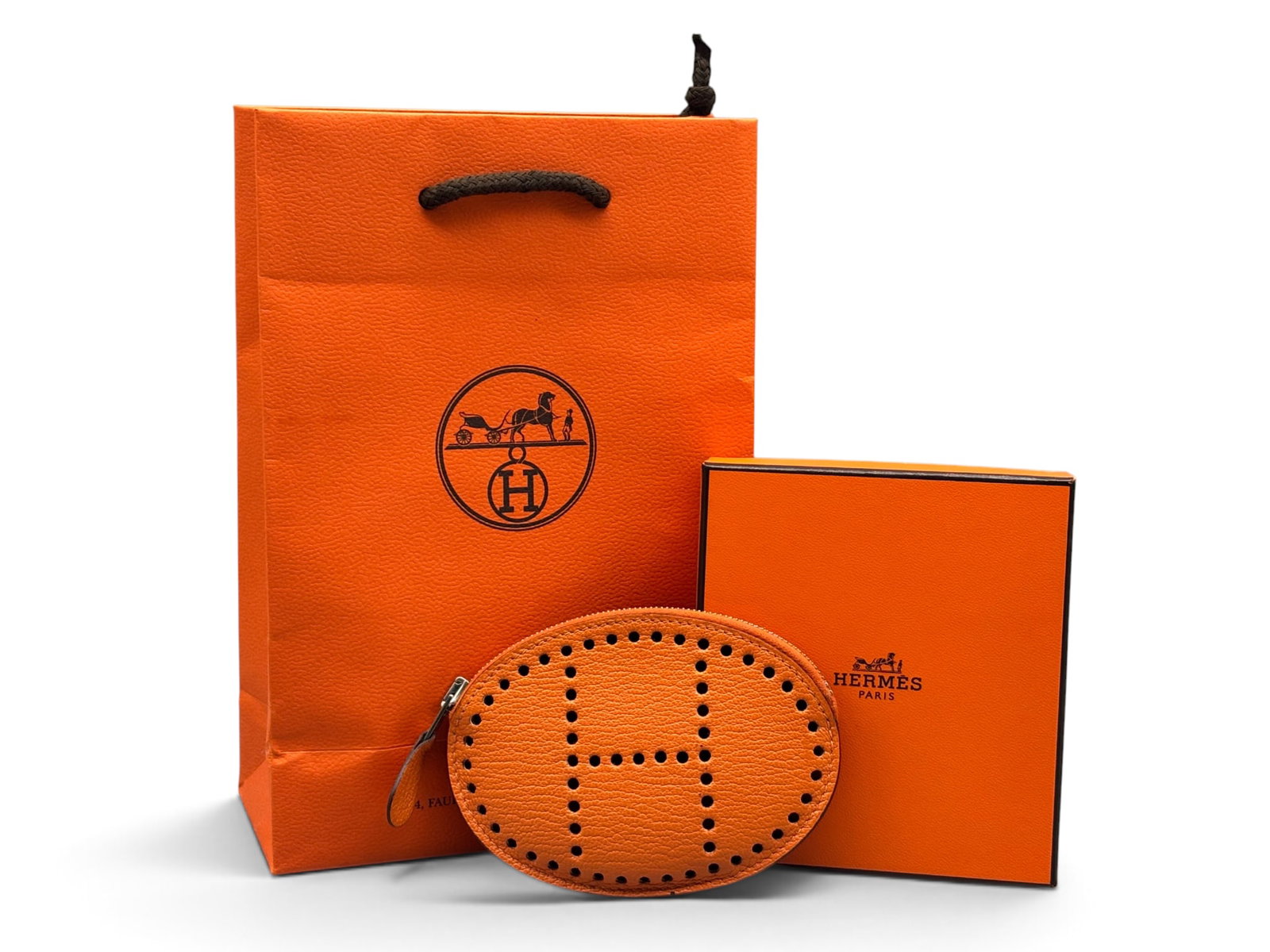 Hermes Porte-Monnaie Evelyn Chevre Coin Purse: An Hermes Paris Porte-Monnaie Evelyn Chevre coin purse in orange Mysore goatskin leather. Marked Hermes. Includes Hermes box and bag. 3in tall x 4-1/2in wide. | You have additional shipping options, a
