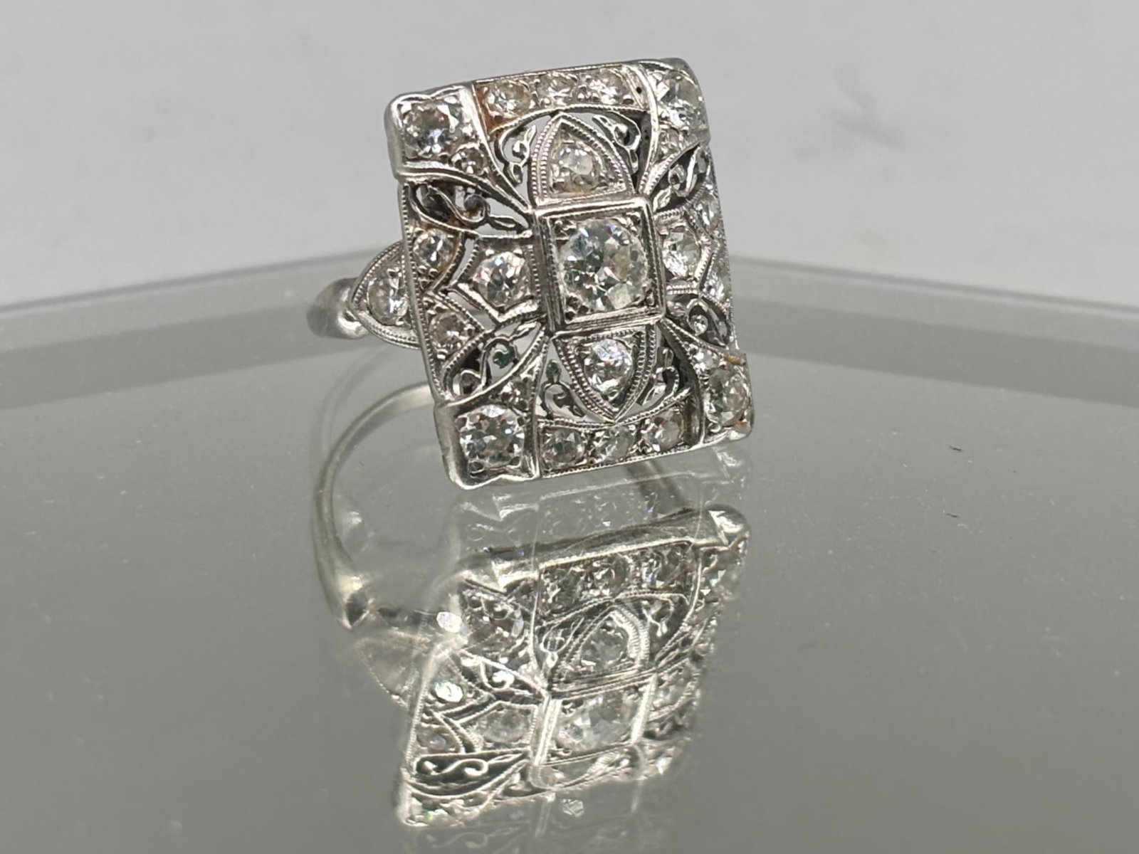 Art Deco Platinum and Diamond Ring: An Art Deco platinum and iridium ring in an ornate rectangular form with 21 inset diamonds flanked by milgrain and filigree detail. Band is marked 10% iridium 90% platinum. Size 6. 3.47 dwt. | You hav