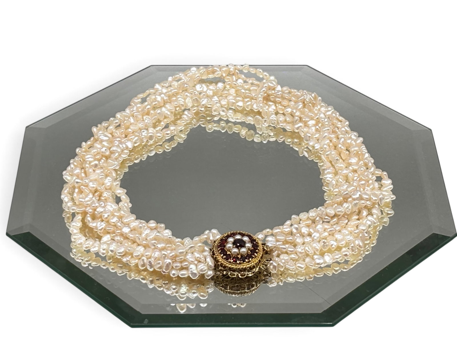 14K Garnet and Freshwater Pearl Necklace: A freshwater pearl multi-strand necklace with 14K yellow gold filigree clasp adorned with center circular cut garnet surrounded by 15 garnets. Marked 585. 19in long. | You have additional shipping opt
