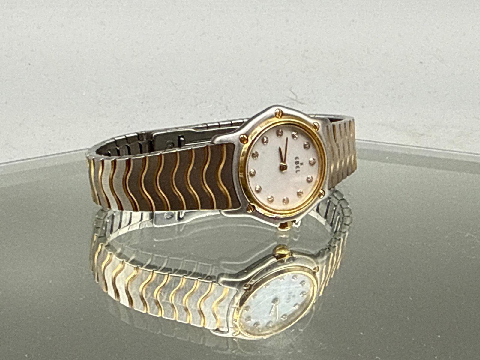 Ebel Classic Wave Wristwatch: An Ebel classic wave stainless steel watch having an 18K gold bezel with mother of pearl face and diamond hour markers. 2in diameter. | You have additional shipping options, and are not required to us