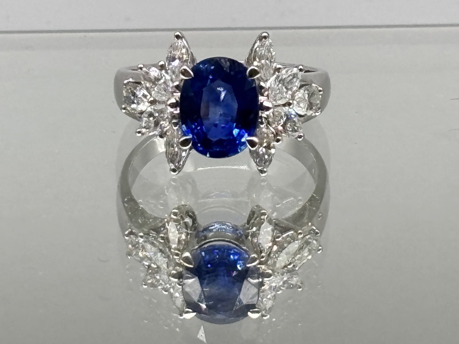 18K Oval Cut Sapphire and Diamond Ring: An 18K white gold ring with an oval cut sapphire flanked by ten marquise cut diamonds. Marked 750 on interior. Size 7. 3.72 dwt. | You have additional shipping options, and are not required to use Liv