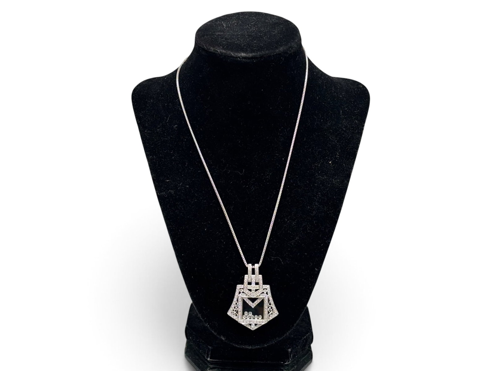14K Art Deco-style Floating Diamond Pendant Necklace: A 14K white gold pendant of Art Deco geometric and filigree design, encrusted with pave diamonds and featuring a center with seven floating diamonds encased in glass. Marked 14K. Chain is 18in long. P