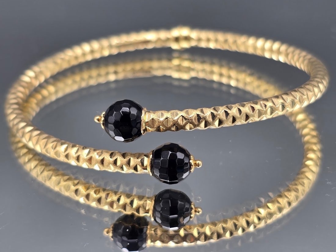 14K Bypass Cuff Bracelet: A 14K yellow gold bracelet of corrugated texture in a bypass cuff design, terminating in black glass beads. Marked 14K Italy on interior. 2-5/8in wide. 3.98 dwt. | You have additional shipping options