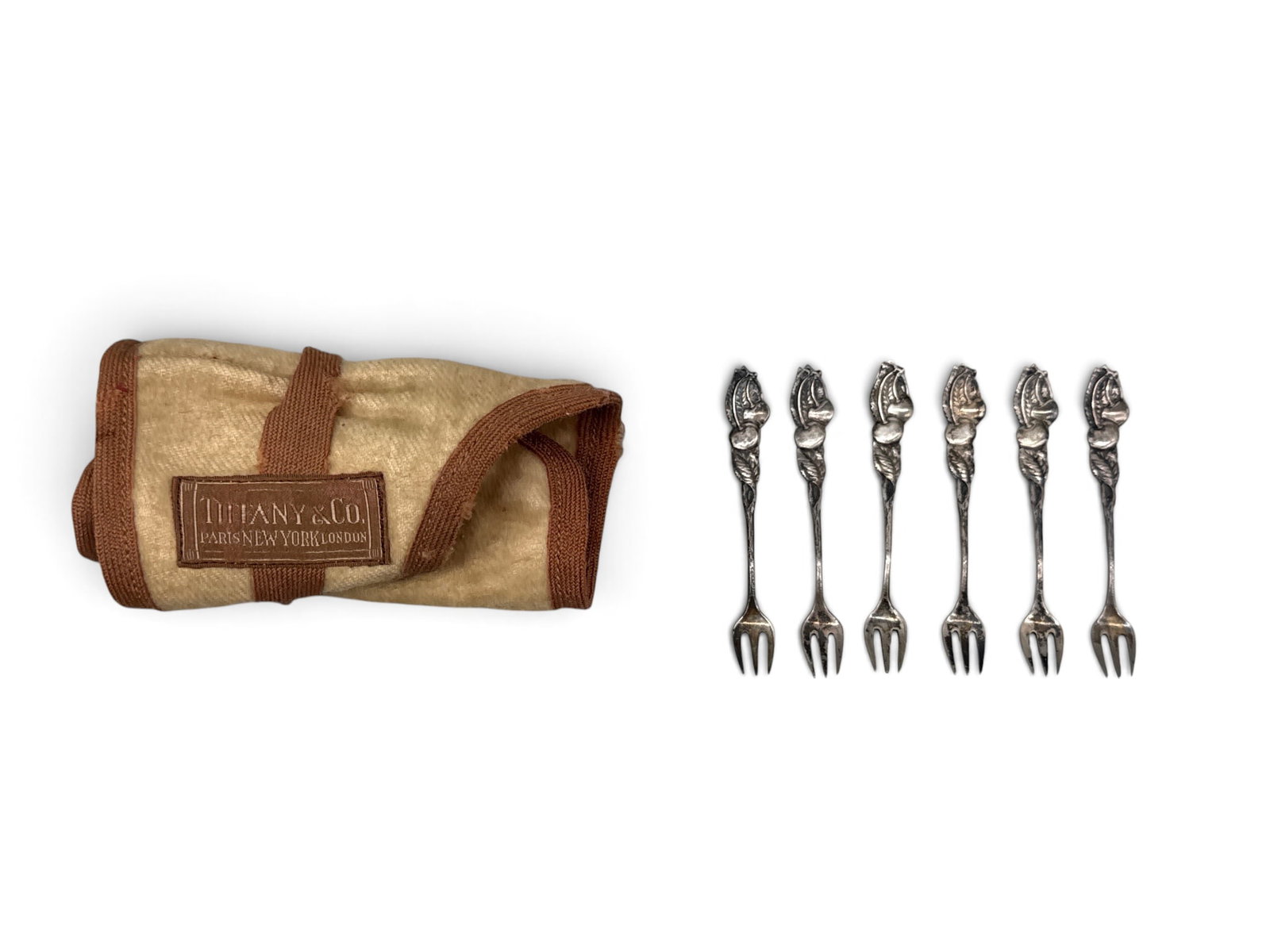 Six Tiffany & Co. Sterling Cherry Cocktail Forks: A set of six Tiffany & Co sterling silver cocktail forks with cherry motif. Marked Tiffany & Co. Includes original dust cloth. 2-3/4in long. 0.911 ozt. | You have additional shipping options, and are