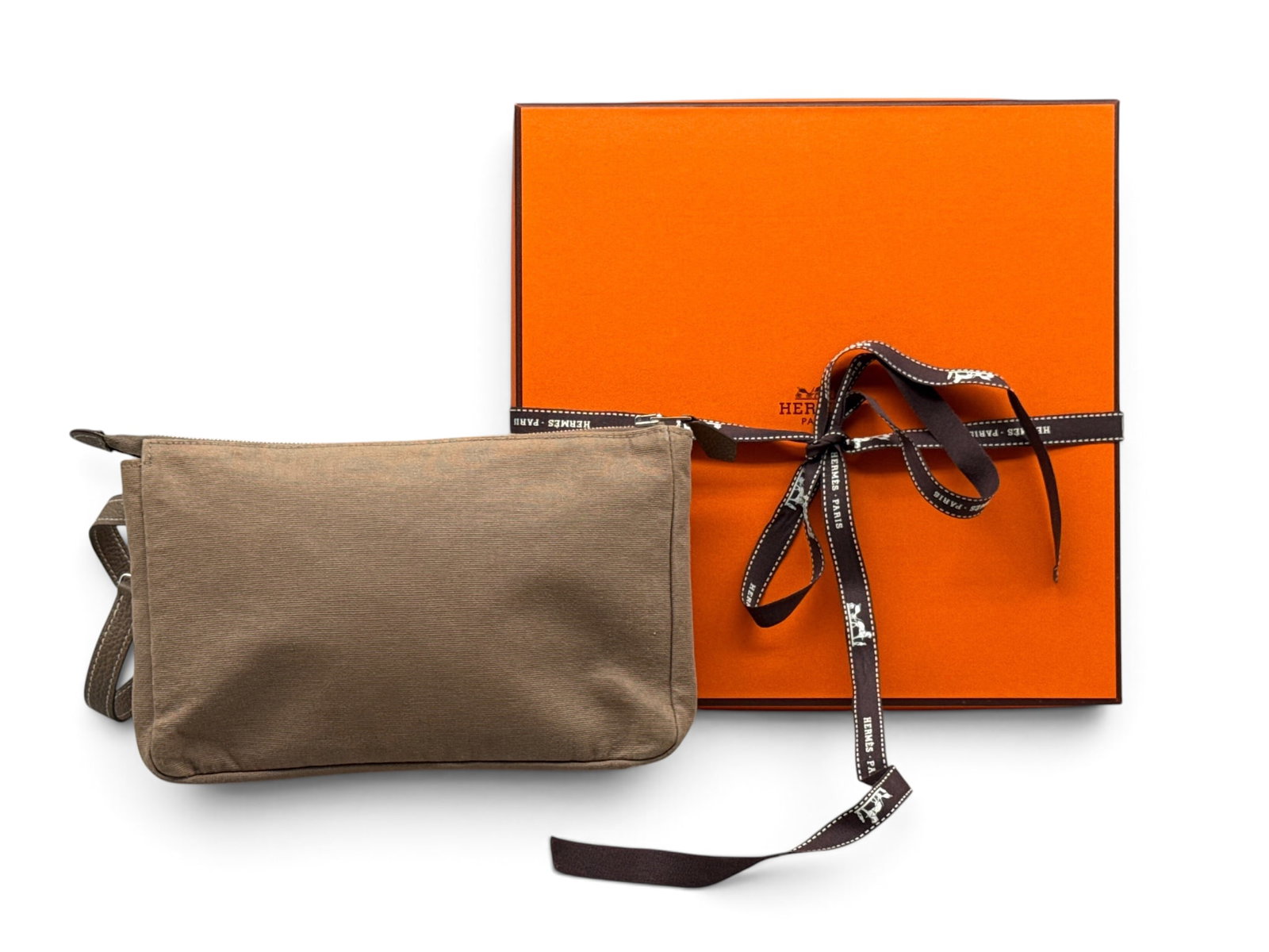 Hermes Etoupe Canvas and Leather Wristwallet: An Hermes Etoupe canvas wristwallet with leather straps. Hardware is marked Hermes; Hermes tag inside. Includes Hermes box and ribbon. 5-1/2in tall x 9in wide. | You have additional shipping options, 