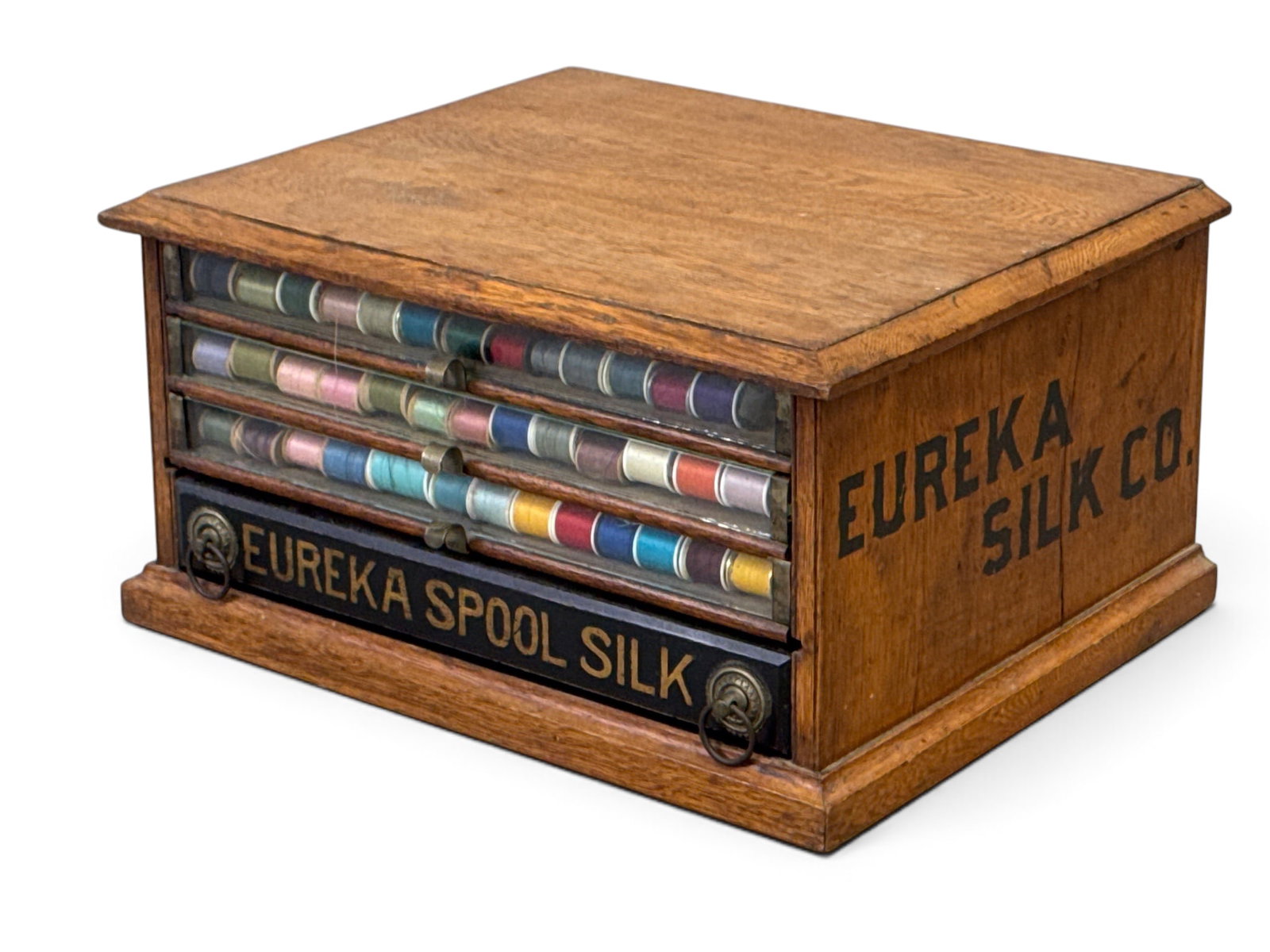 Eureka Oak Spool Cabinet: An Eureka oak spool cabinet with glass drawer fronts and stenciled advertising sides. 11in tall x 21in wide x 17in deep. | You have additional shipping options, and are not required to use Live Shippi