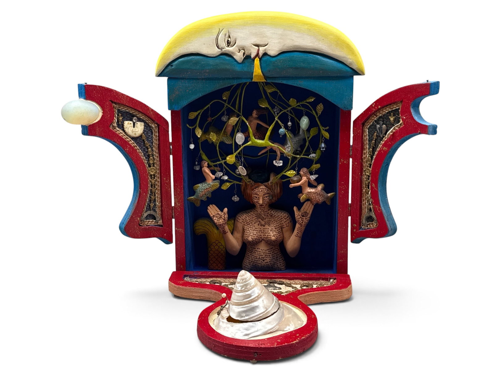 Folk Art Surrealist Wooden Shadow Box Shrine: A Folk Art surrealist wooden shadow box shrine with carved crescent moon exterior and conch shell door raised to reveal a wooden deity adorned with writing and a nest of mermaid figures. 15in tall x 9