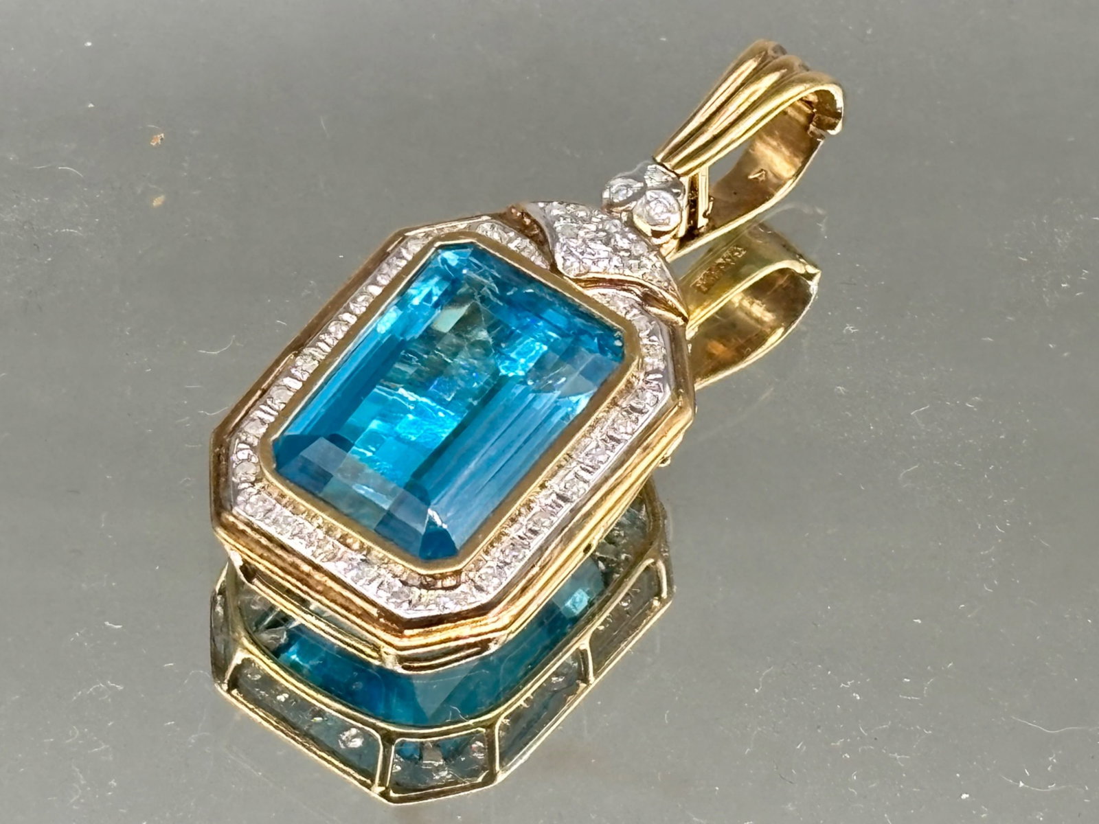 14K Pendant with Emerald Cut Topaz and Diamonds: A 14K yellow gold pendant set with an 11.6 carat emerald cut topaz, surrounded by a halo of diamonds mounted in white gold. Pendant is marked 585. 1-1/2in tall x 3/4in wide. 6.88 dwt. | You have