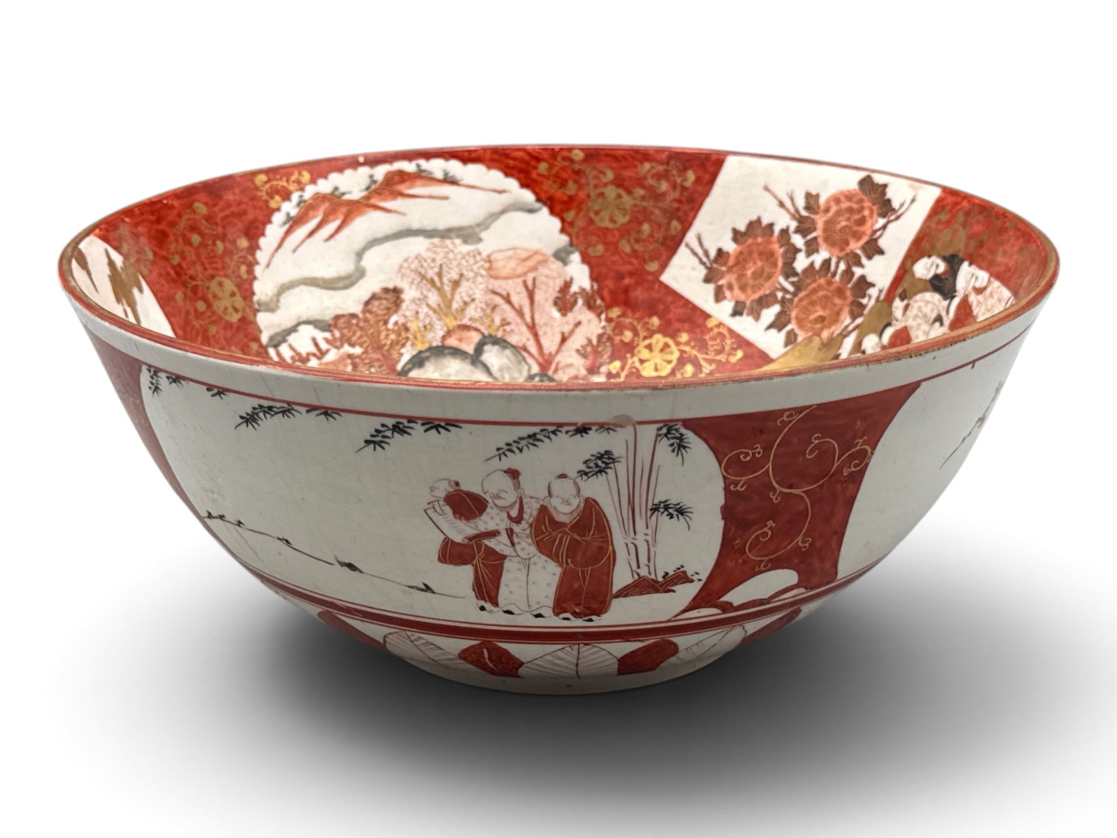 Japanese Kutani Porcelain Serving Bowl: A Japanese Kutani porcelain bowl having an iron red background with gilt decorated ceremonial figures surrounded by a botanical scene. Signed. 5in tall x 12in wide. | You have additional shipping