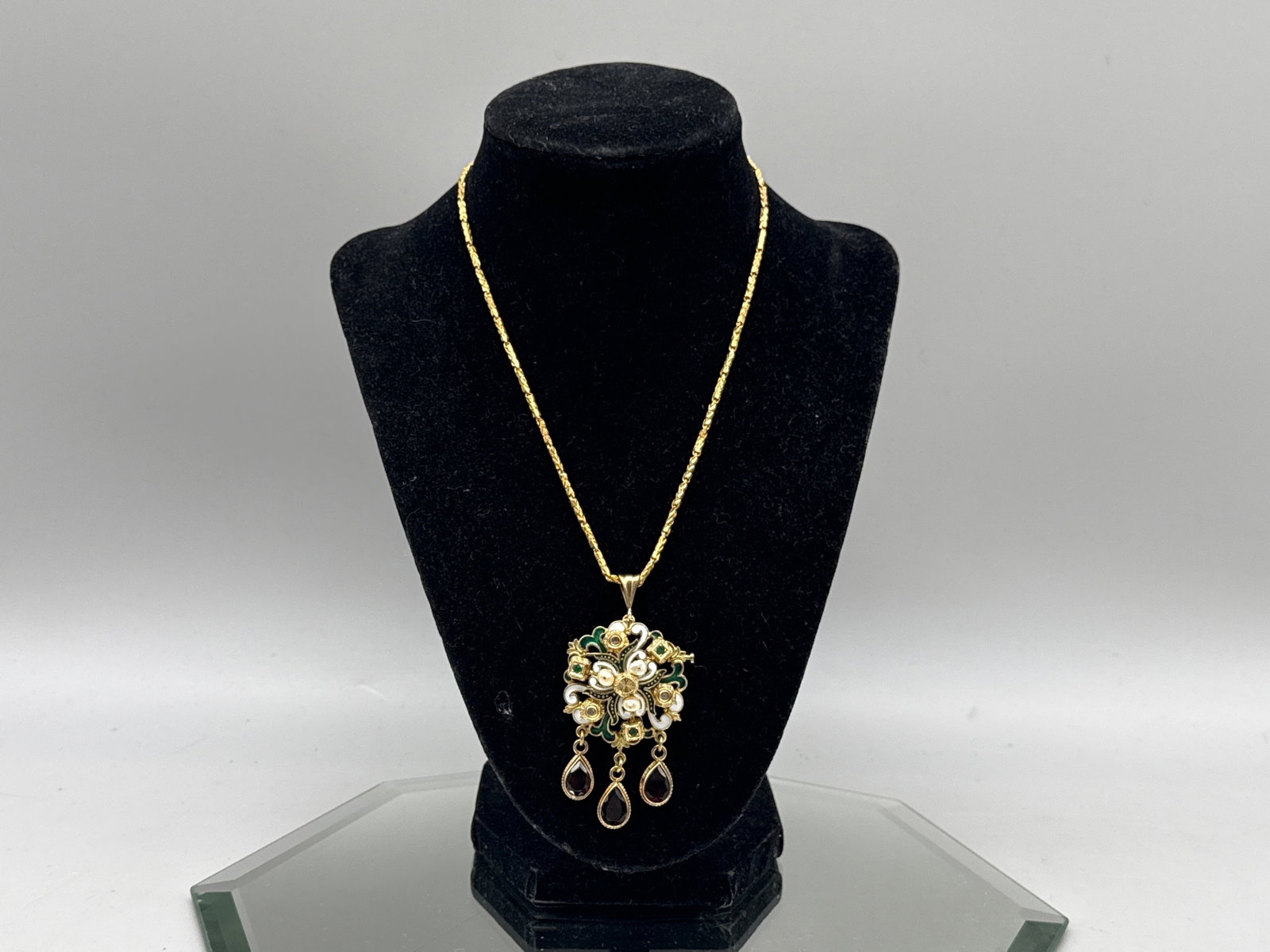 14K/24K Enameled Diamond and Emerald Pendant: An ornate 14K and enameled pendant with pearl, diamond, emerald and garnet, on a 24K yellow gold chain. Pendant tests as 14K. Chain is hallmarked. Pendant: 1-1/2in tall x 2in wide. Chain: 22in long.