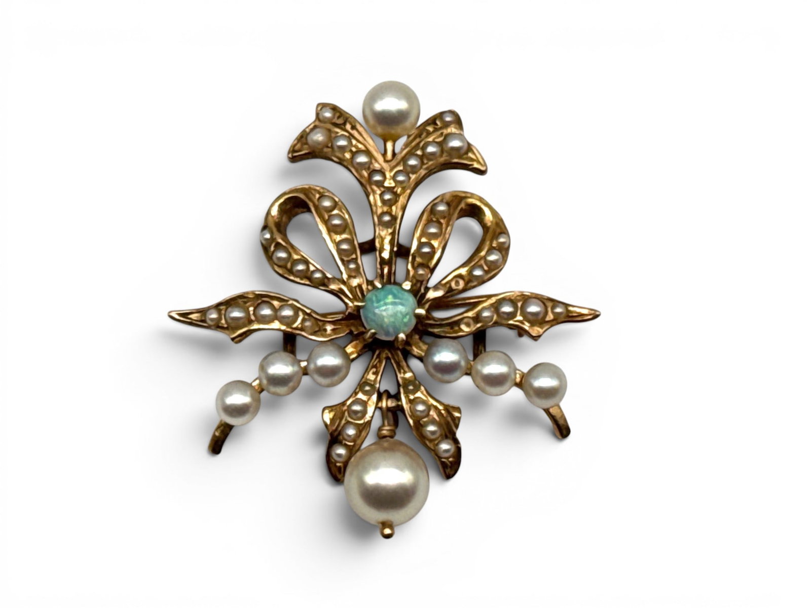 14K Opal and Pearl Brooch: A 14K yellow gold brooch of ribbon bow form with dangling cultured pearl, surrounding seed pearls, and a central set 0.14ct opal. Includes an Independent Gemological Services appraisal circa 1995. 5.6