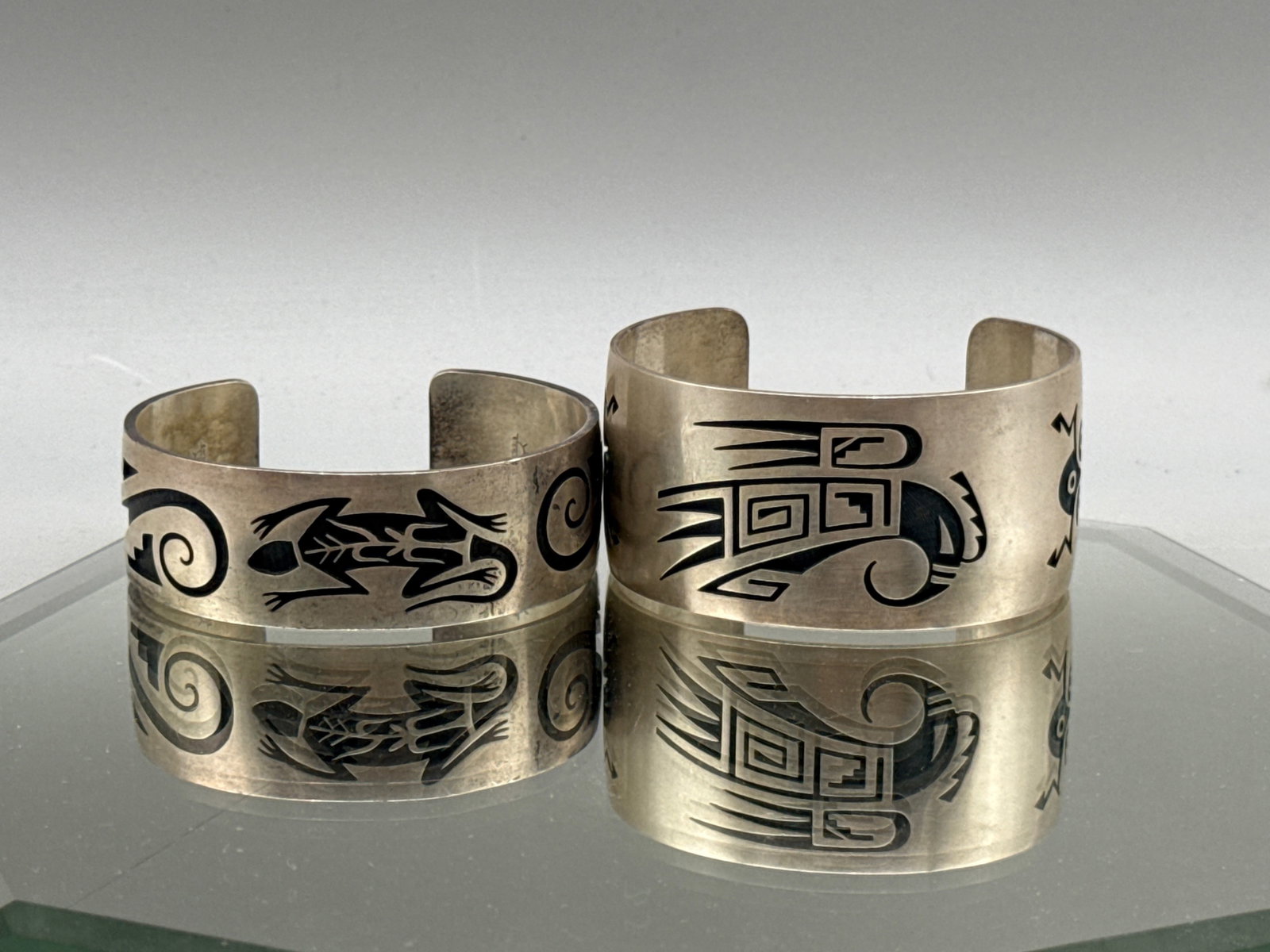 Two Hopi Sterling Tribal Cuff Bracelets: Two Hopi Sterling silver cuff bracelets with stylized, geometric designs of natural elements. Hallmarked with Sunface and Sterling. 124.03 dwt. Larger: 1-1/2in tall x 3in wide. | You have additional