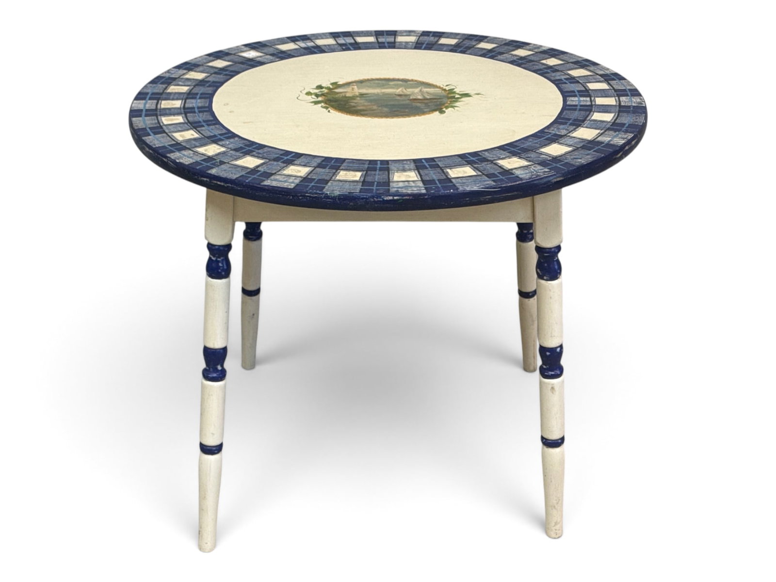 New England Folk Art Painted Table: A New England folk art painted table having a circular top painted with a coastal scene with lighthouse, raised on turned legs. 22-1/4in tall x 27in wide. | You have additional shipping options, and