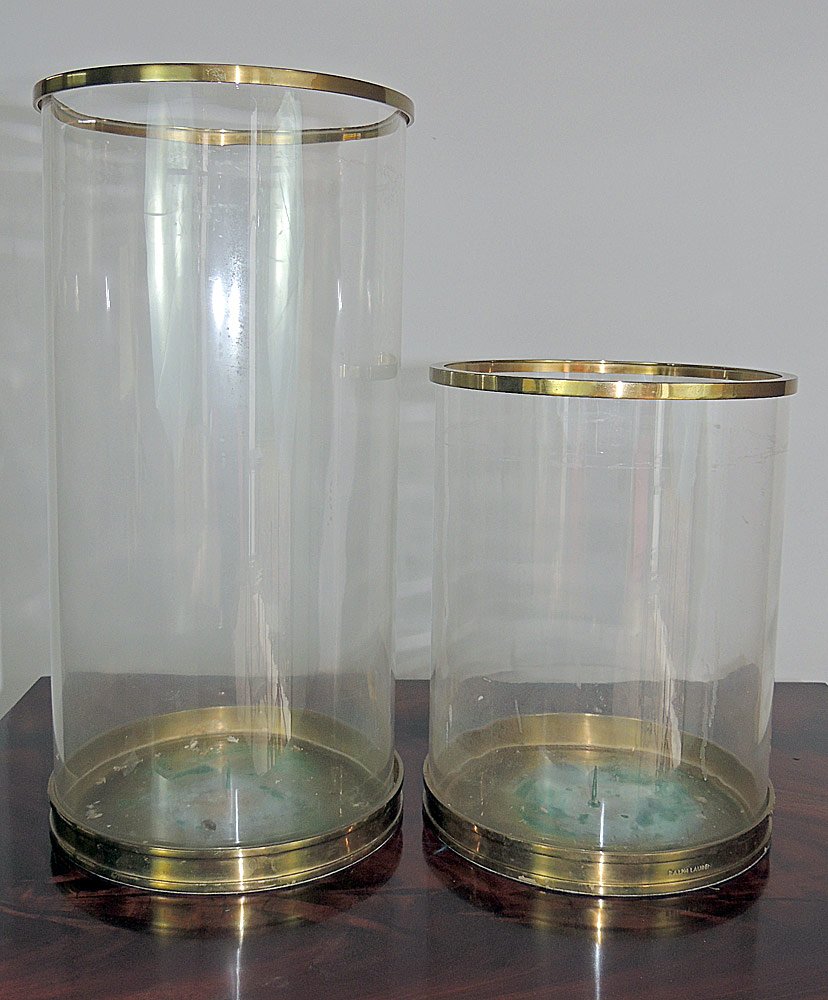 Two Brass and Glass Hurricanes: Two Ralph Lauren glass hurricane shades with brass bases. 18" and 11" tall, 9" diameter.