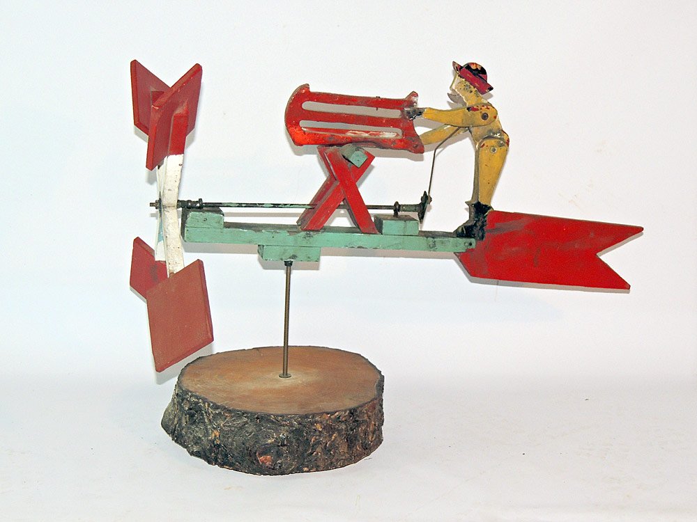 Painted Whirligig: Paint-decorated wooden whirligig of a man sawing, mounted on natural wood stand. 28" long.