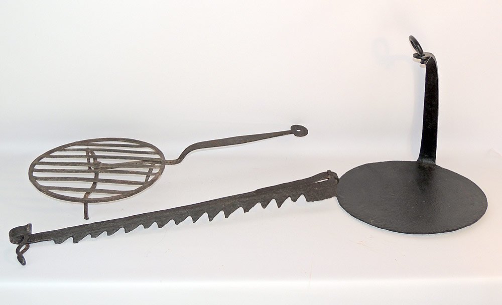 Antique Iron Hearth Articles: Grouping to include an early sawtooth trammel; an iron griddle; a tri-footed rotating gridiron. Gridiron: 29" long. Provenance: From a prominent estate in historic New Castle, DE.