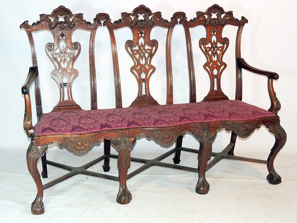 English Mahogany Triple Chair- Back Settee: 19th century. Chippendale style. Ornately carved with cross stretcher and ball and claw feet. 43" tall x 61" wide x 19" deep.