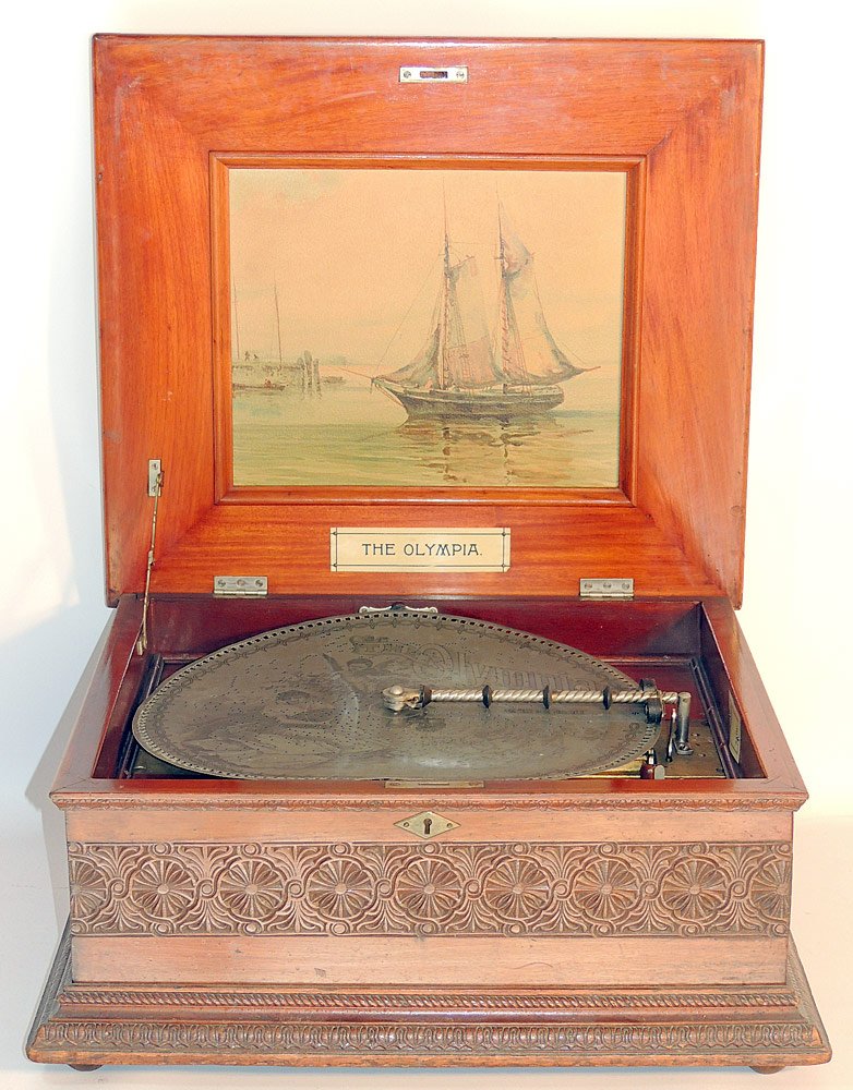 Olympia Double-Comb Music Box: With carved mahogany case raised on feet. Hinges top reveals a harbor scene lithograph. Original labels. Together with singular disc. Box 10" tall x 21-1/2" wide x 19" deep.