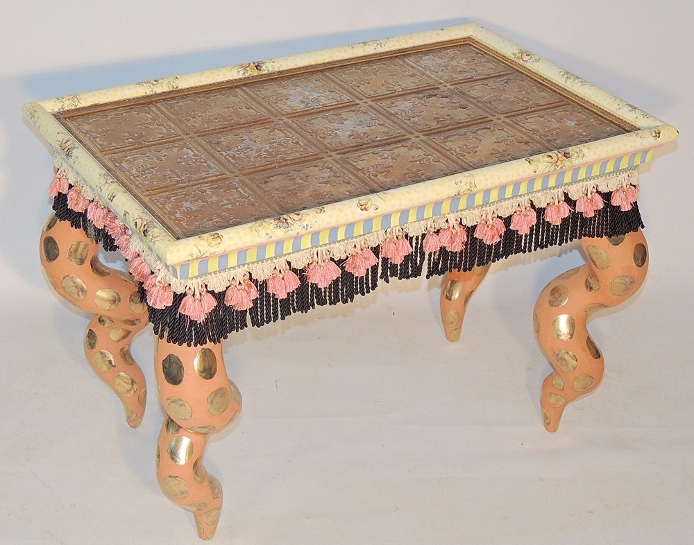MacKenzie Childs Cocktail Table: With embossed and distressed metal top, painted ceramic twist legs, and fringed apron. 23" tall x 33-1/2" wide x 22" deep.