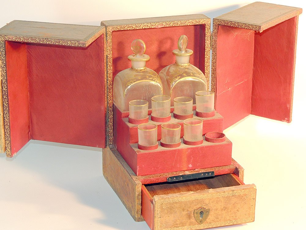 Antique Faux Book Bottle Case Decanter Set: Antique faux book bottle case decanter set. With a cabinet revealing two decanters and 7 glasses with gilt trim. Case: 11-1/2" tall x 7-3/4" wide x 9" deep. Provenance: From the Estate of Albert M. an