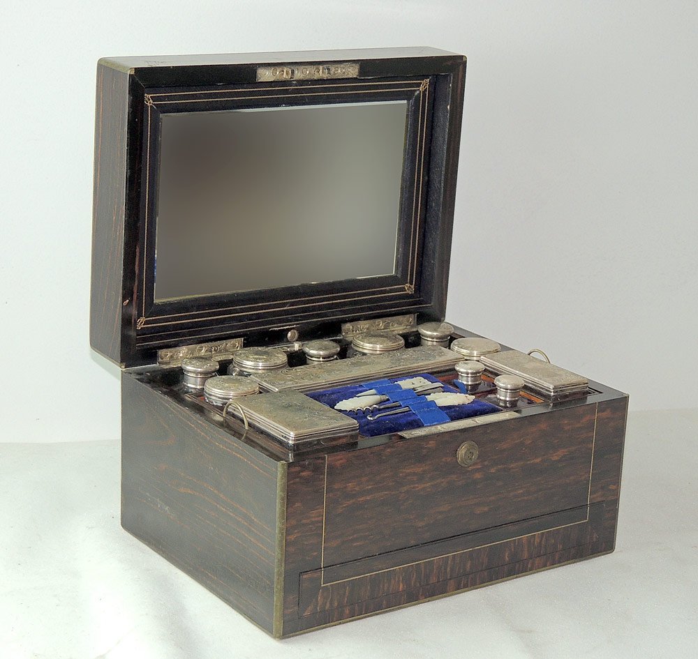 English Regency Toiletry Set: English Regency toiletry set in rosewood case. Hinged top opens to reveal a fitted interior with sterling boxes, sterling-topped jars, and other grooming implements. Lids are hallmarked "WN" with "D" 