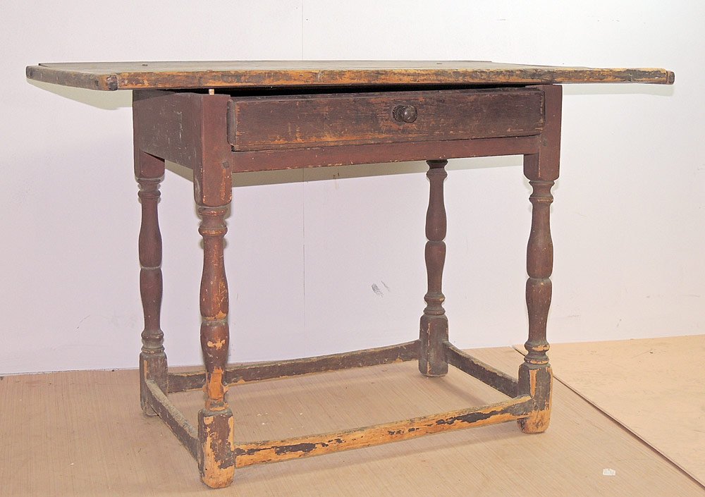 Early 19th C. Pine Tavern Table: Early 19th Century pine tavern table, with an overhang top with bread-board ends, and single drawer. The turned legs are joined by a stretcher base. Base retains a red wash. 25 x 38 x 23 in.