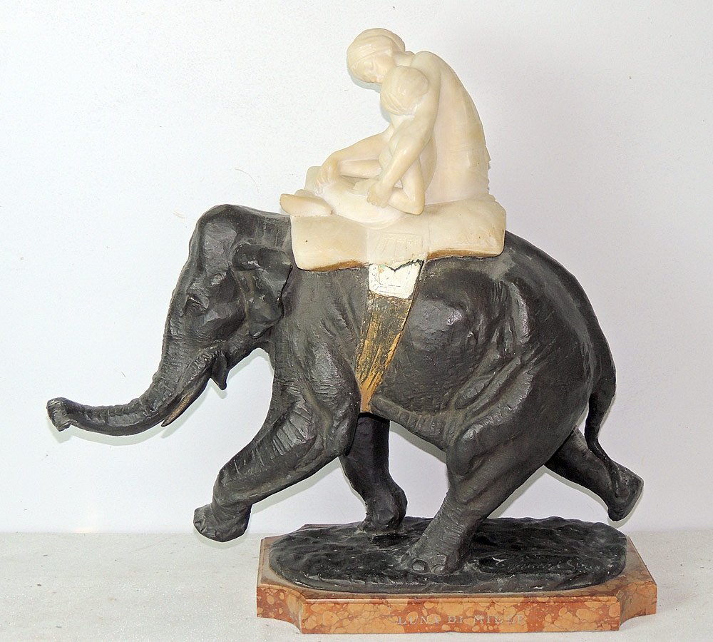 Sirio Tofanari, Bronze and Alabaster Elephant: Sirio Tofanari sculpture of cast bronze Asian elephant with two riders carved from alabaster. Mounted on a raised marble base marked "Luna De Miele". Bronze signed in cursive. The reverse of the marbl