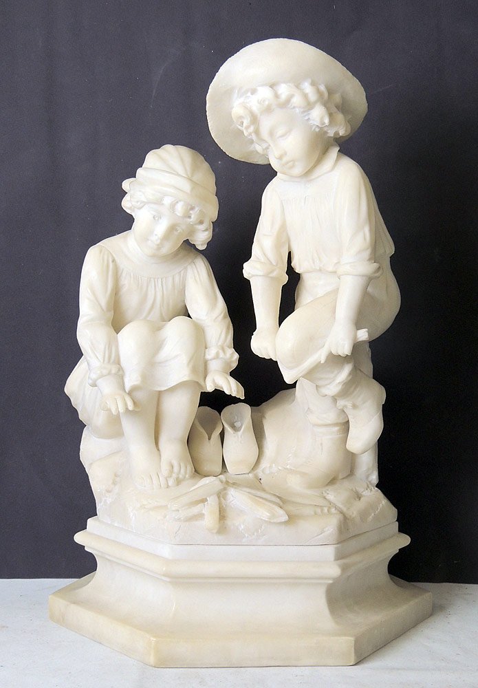 Adolfo Cipriani, Alabaster Boy and Girl: Adolfo Cipriani alabaster sculpture of a boy and a girl tending a fire, mounted on a raised base. Signed on reverse, "A. Cipriani" 21-1/2 x 14 x 10 in.