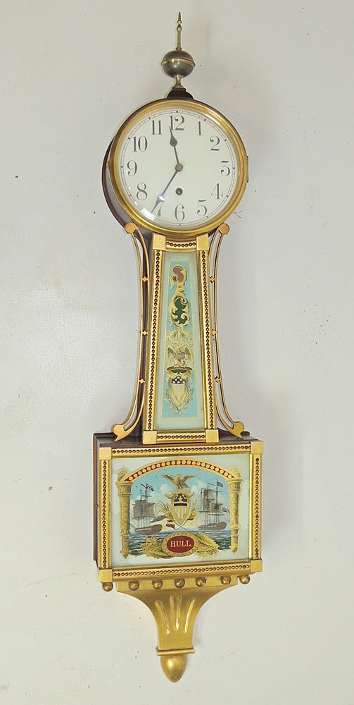 Waterbury Banjo Clock: Waterbury banjo clock with porcelain dial and reverse-painted panel with naval battle scene, titled "Hull". 44 x 10 in.