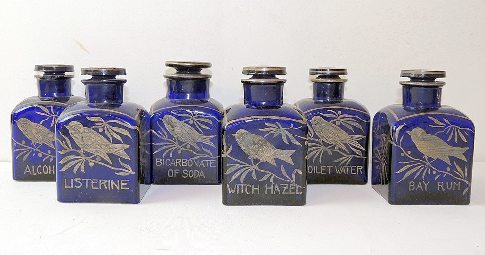 Six Czech Cobalt Glass Toiletry Bottles: A matched set of six Czechoslovakia cobalt glass toiletry bottles with silver overlaid bird decoration and label. Each with stopper. H: 4-1/2in.