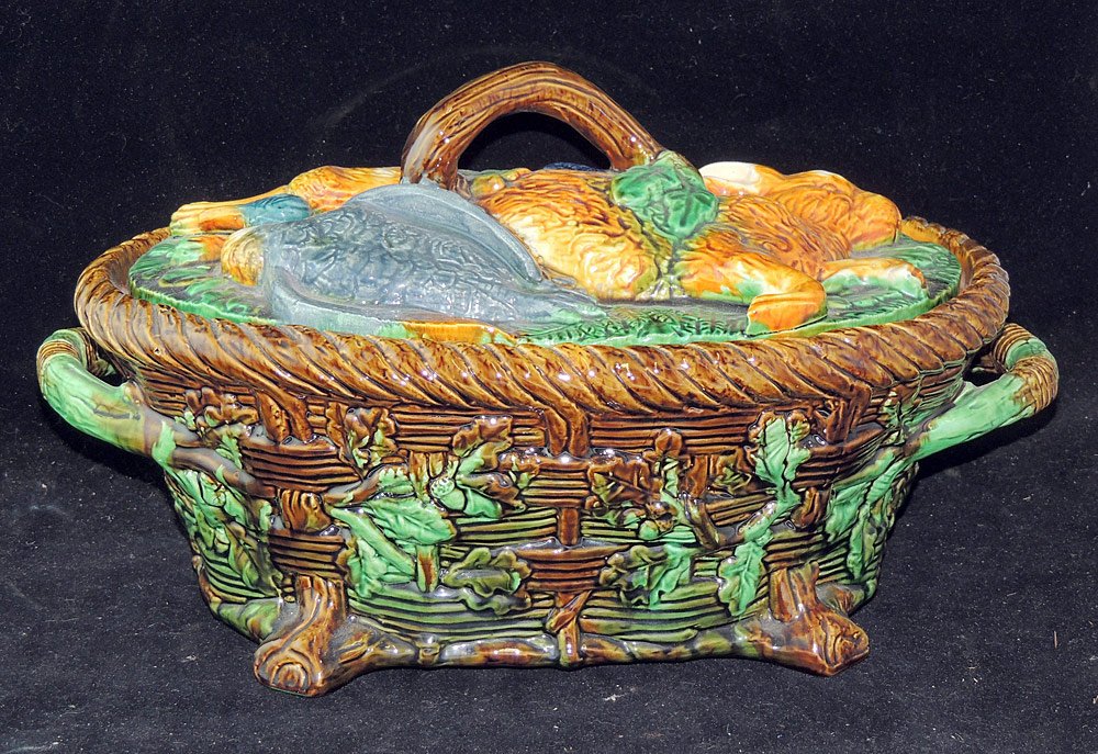 Minton Majolica Porcelain Tureen: Minton majolica game-motif tureen with rabbit and fowl decorated lid on a basket-weave base with twig handles and tree branch feet. 8-1/2 x 14 in.