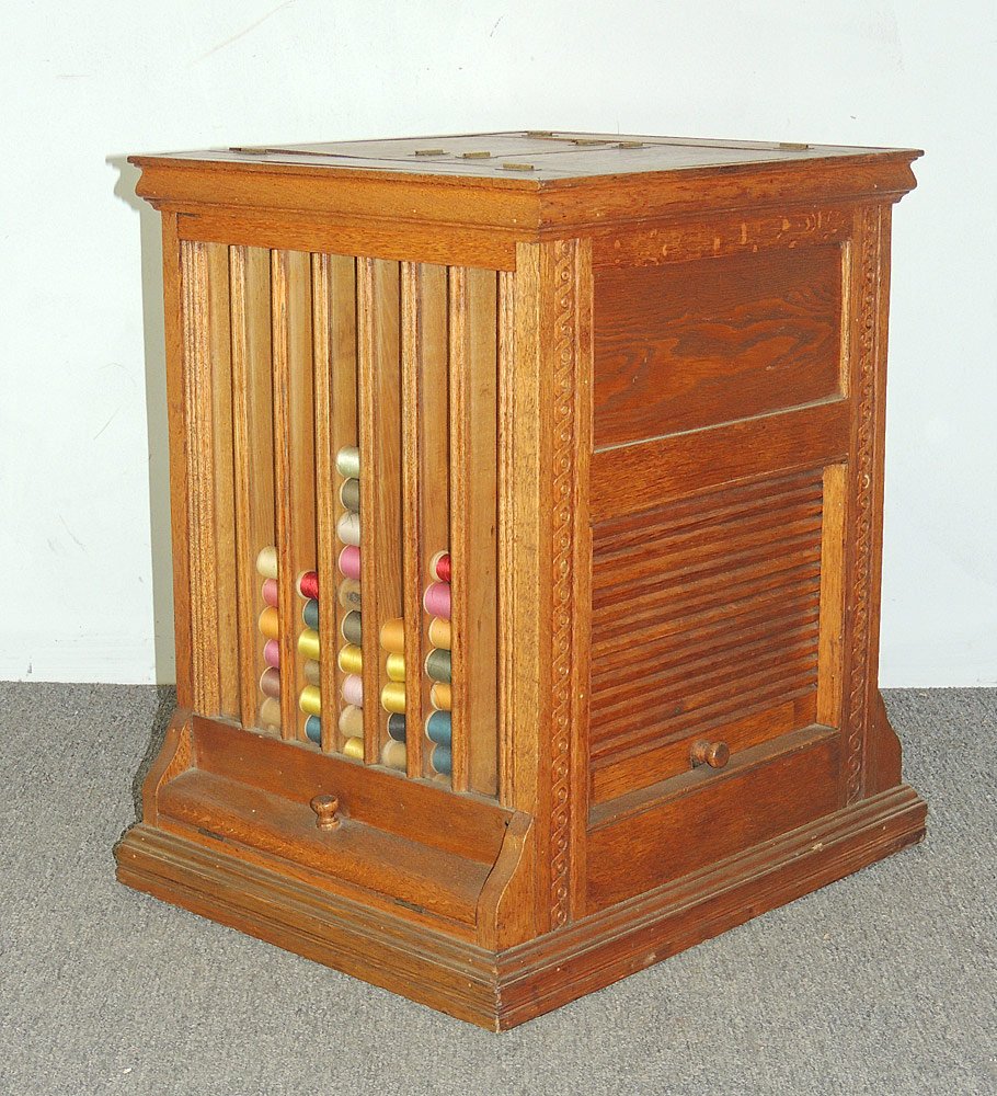 Countertop Oak Revolving Spool Cabinet: Countertop revolving oak spool cabinet. With roll up sides and glass display sides. Numerous compartments. 23 in tall x 16-1/2 in wide x 17-1/2 in wide.