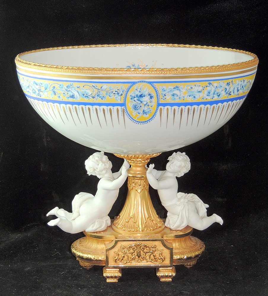 Sevres Style Gilt Bronze and Porcelain Centerpiece: Sevres style gilt bronze and porcelain centerpiece. With two parian porcelain figures on a gilt bronze bae supporting as porcelain compote decorated with blue and gold flowers. Marked "Decortiche". 14