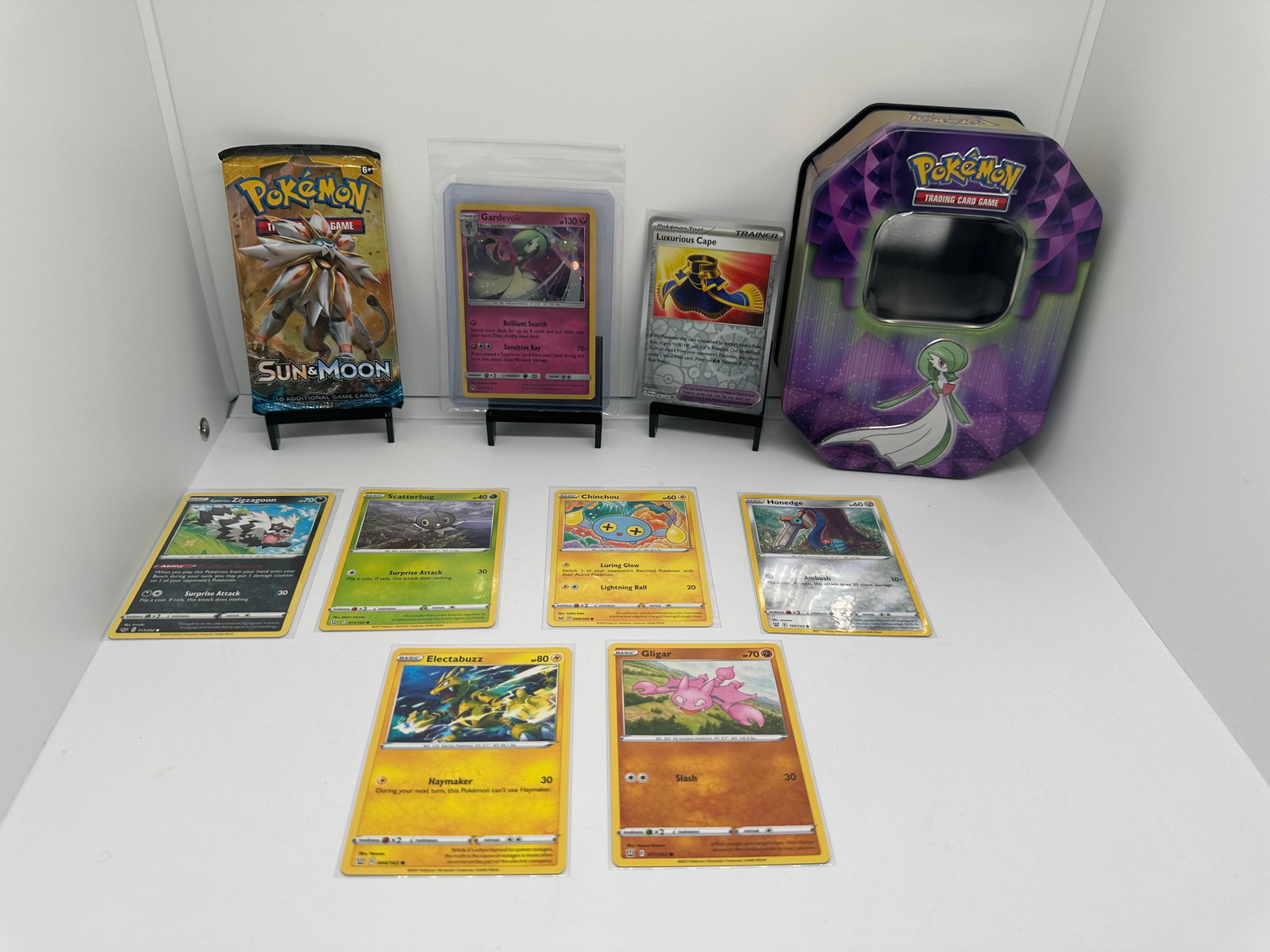 TCG Pokemon Sun & Moon base, Gardevoir: (9) TCG Pokemon cards from various sets and years. Add to your playing decks or complete your master sets. * Sun & Moon base pack * Gardevoir Holo & tin empty * Luxurious Cape Reverse Holo & more.