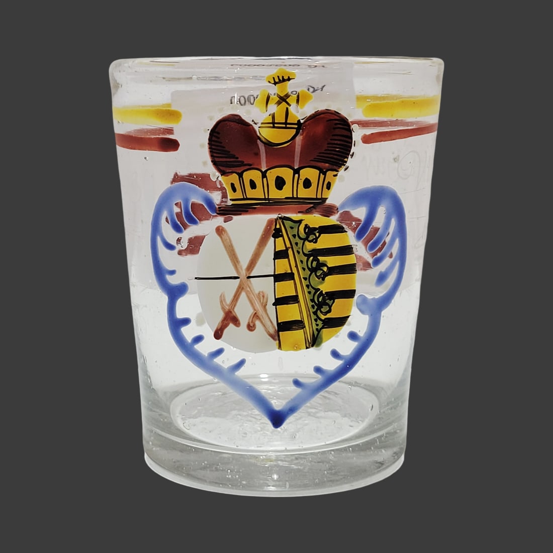 Biedermeier Period Beaker, Bohemian Beaker, Saxon Royal Crested Beaker: 3 1/8" Tall by 2 5/8" Wide blown colorless glass with bubbles and impurities, hand enameling with horizontal yellow and red under the rim lines with beautiful crest and florals with a saying, base has