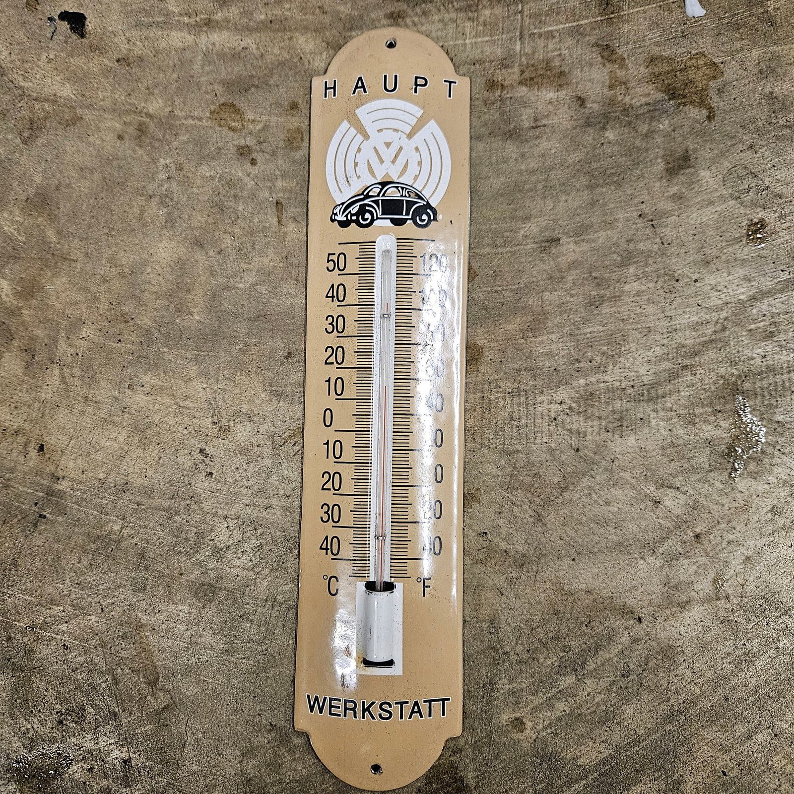 Vintage Haupt Werkstatt Porcelain Thermometer: This porcelain thermometer features a classic car illustration with the text "Haupt Werkstatt," making it a unique piece for vintage car collectors or for display in an automotive repair shop. The neu