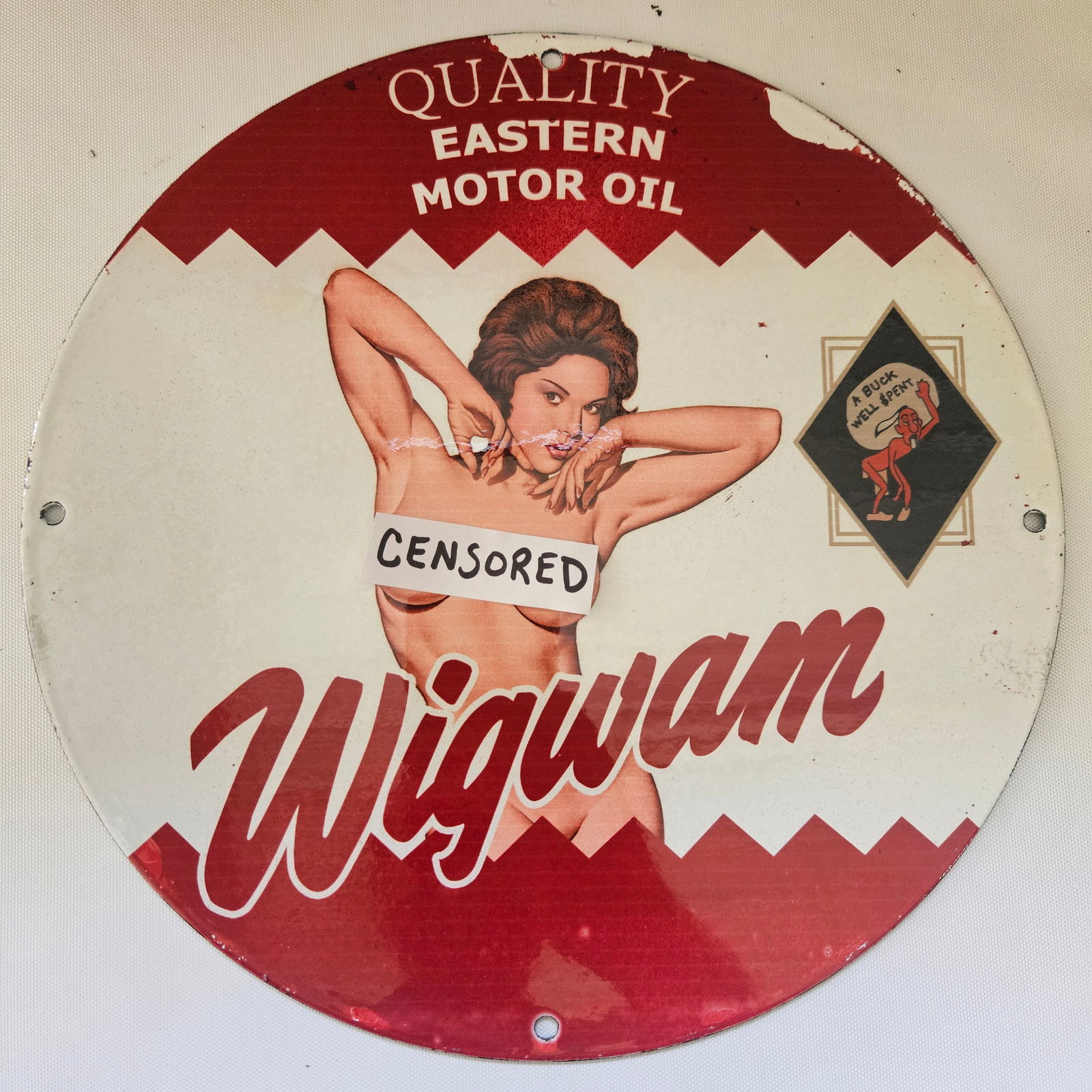 WIGWAM EASTERN MOTOR OIL GAS OIL GARAGE MAN CAVE PORCELAIN SIGN: This advertisement features a Native American chief wearing a feathered headdress. The text "Wigwam Eastern Motor Oil" circles the chief's image. Below him are the words "Lubricates Protects." Measuri
