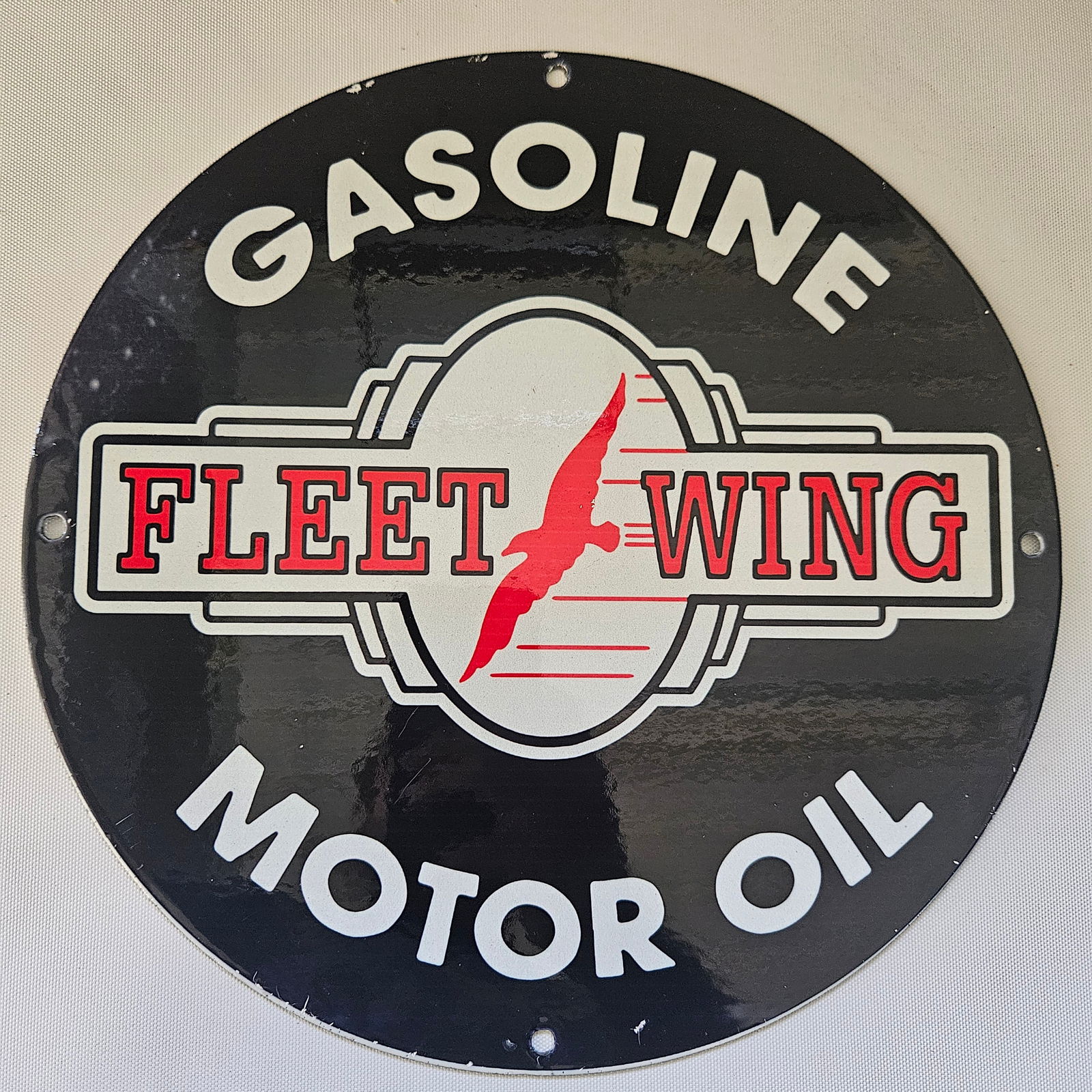 FLEET WING GASOLINE MOTOR OIL GAS OIL GARAGE MAN CAVE PORCELAIN SIGN: The 12-inch FLEET WING GASOLINE MOTOR OIL advertisement captures a bygone era of automotive enthusiasm and the golden age of motoring. Its vibrant colors and classic design reflect the charm and allur